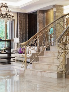 Staircase with intricate metal balusters and marble surface