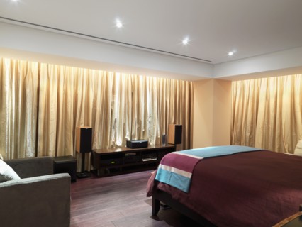 Bedroom with gold curtains and hardwood floor
