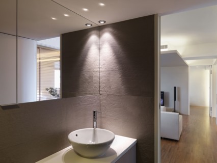 Bowl sink in bathroom and hardwood floor leading down hallway