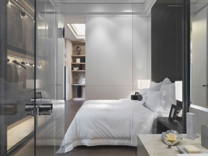 Glass door and wall separating modern bedroom from bathroom