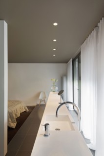 View of faucet and sink along curtained window and cropped bed at home