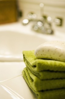 Stack of Green Towels with Soap on Bathroom Counter