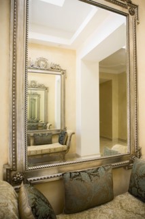 Detail of a large wall mirror over a loveseat with decorative pillows