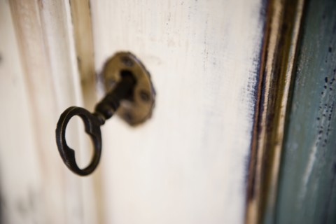 Image of aged key in keyhole.
