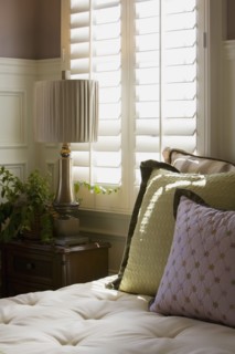 Purple and green decorative pillows on bed near window