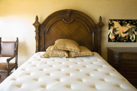 Large unmade bed with three pillows and wooden headboard