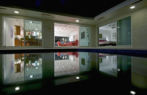 Night view in towards living room of home across pool