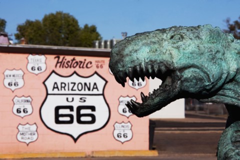 Close up of dinosaur statue by Historic Route 66 sign
