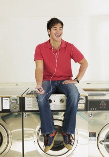 Asian man listening to mp3 player in laundromat