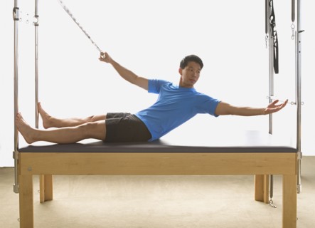Asian man stretching on exercise equipment