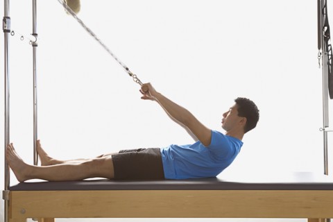 Asian man stretching on exercise equipment