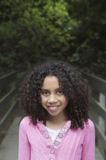 Mixed race girl crossing wooden bridge