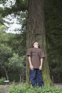 Mixed race boy leaning on tree trunk