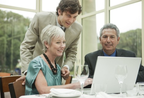 Business people using laptop at table in restaurant