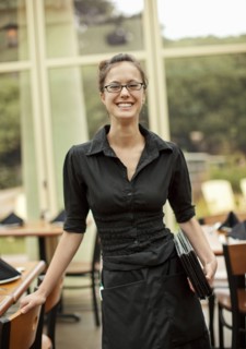 Portrait of smiling Hispanic waitress holding menus in restaurant
