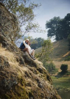 Caucasian couple sitting on hill near river