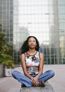 Portrait of serious mixed race woman sitting near highrise