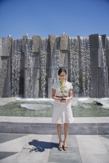 Asian woman holding seedling near fountain