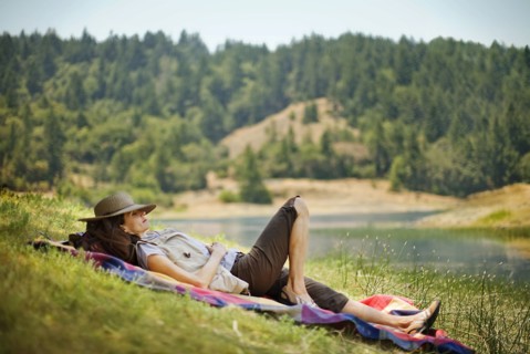 Hispanic woman relaxing on blanket near river