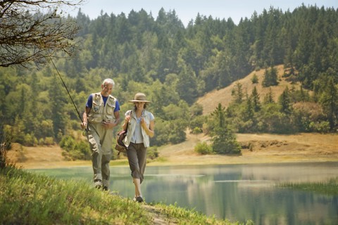Couple walking with fishing rod near river