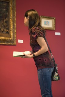 Middle Eastern woman admiring painting in museum