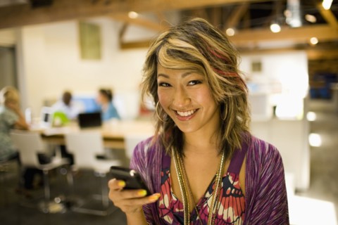 Japanese businesswoman using cell phone in communal workspace