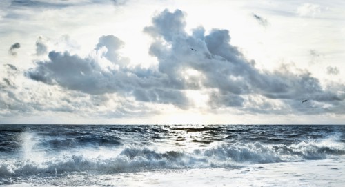 Cloudy sky over stormy waves on beach