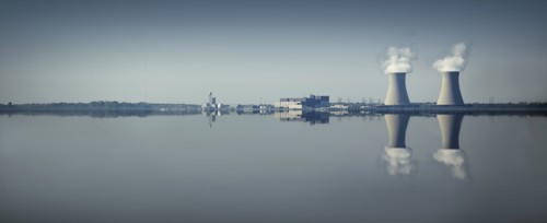 Smoke stacks and factory reflected in still lake