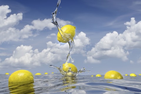 Lemons splashing into pool of water