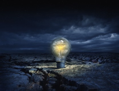 Illuminated light bulb in cracked earth