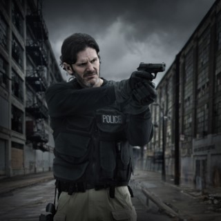 Caucasian policeman aiming gun on city street