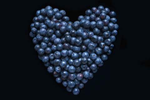 Blueberries in shape of heart on black background