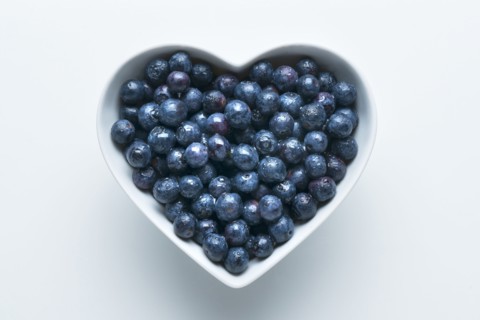Blueberries in heart-shape bowl on white background