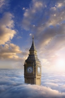 Birds flying around clock tower above clouds