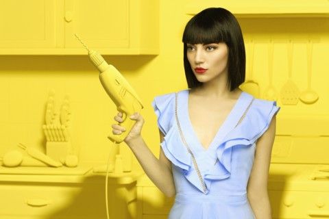 Caucasian woman in yellow old-fashioned kitchen holding power drill