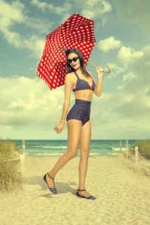 Caucasian woman holding polka-dot umbrella at beach