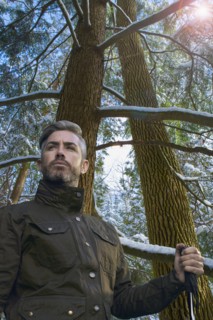 Caucasian hiker holding walking stick under snowy tree