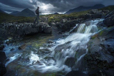 Caucasian woman hiking near river flowing over rocks