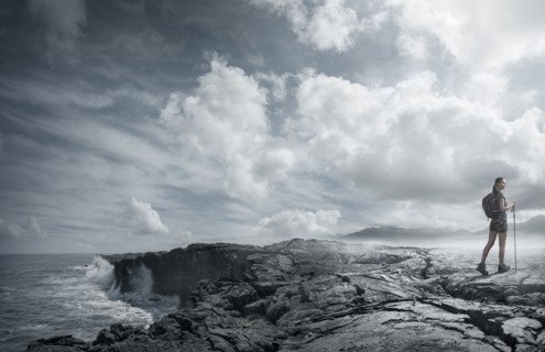 Caucasian woman hiking on rocks near ocean