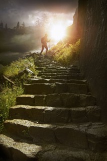 Distant hiker on stone staircase at sunset