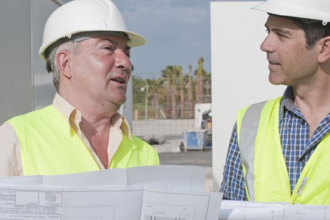 Hispanic construction workers reviewing blueprints