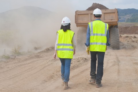 Construction workers walking behind dump truck