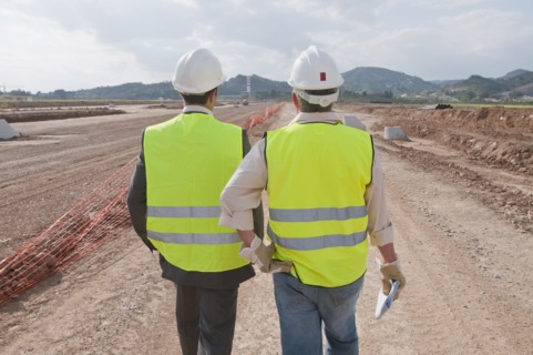 Hispanic businessman and construction worker standing in field