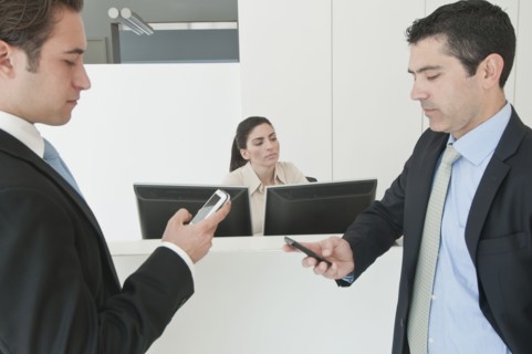 Hispanic businessmen holding cell phones in office