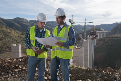 Construction workers looking at blueprint at construction site