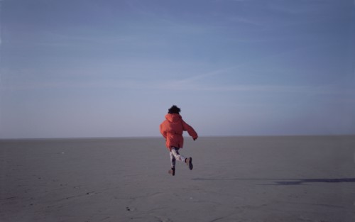 Woman running on sand flats rear view