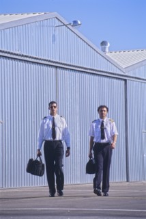 Two pilots walking in front of hangars