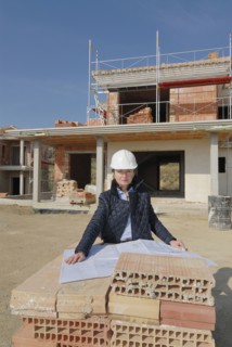 Female architect on construction site looking at plan portrait