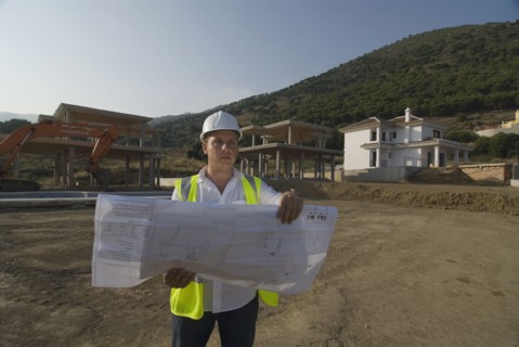 Male engineer wearing hard hat looking at plans on building site