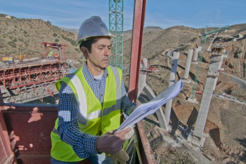 engineer with plans at bridge construction site